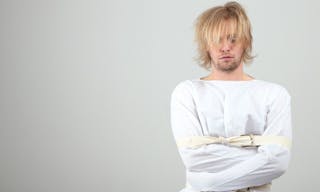 Mentally ill man in strait-jacket on gray background