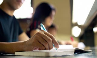 Students doing homework and preparing exam at university, closeup of young man writing in college library