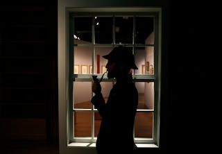 The curator of the exhibition "Sherlock Holmes: The Man Who Never Lived and Will Never Die" poses with a deerstalker hat and a s