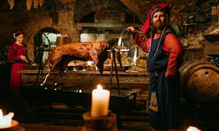 Medieval man doing roasted pig on the rack - Image meat