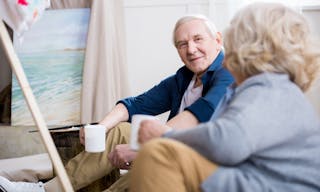 Smiling senior man with coffee cup looking at wife — Photo by ArturVerkhovetskiy