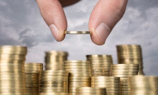 Savings, close up of male hand stacking golden coins over sky background