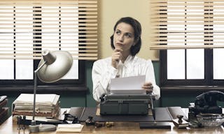 Pensive vintage woman with hand on chin, typing on typewriter and looking for inspiration