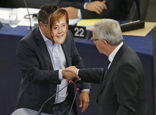 Italian Member of the European Parliament Buonanno wears a mask depicting German Chancellor Merkel as he shakes hands with Europ