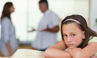 Sad girl with her fighting parents behind her