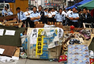 Policemen stand guard behind a barricade set up by pro-democracy protesters, to be removed by bailiffs under a court injunction,