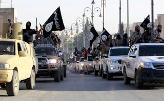 Militant Islamist fighters parade on military vehicles along the streets of northern Raqqa province