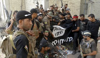 Iraqi security forces hold an Islamist State flag which they pulled down at the University of Anbar, in Anbar province