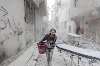 A boy carries his belongings at a site hit by what activists said was a barrel bomb dropped by forces loyal to Syria's President