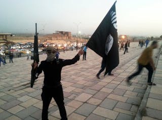 ighter of the ISIL holds a flag and a weapon on a street in Mosul