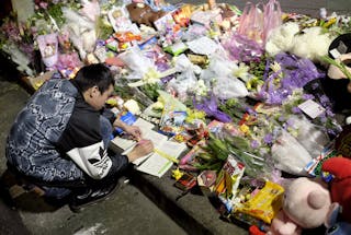 女童斷頭案 隨機殺人 A man leaves a message on a memorial book at a makeshift memorial near the site where a girl was found decapitated, o