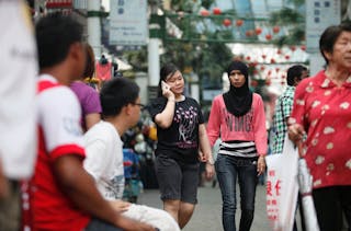 Two women hold hands as they walk along China Town in Kuala Lumpur