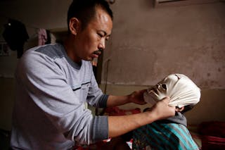 Wang Shouwu helps his son Wang Gengxiang, known as "Masked Boy", wear a mask to prevent his scars from growing and spreading at 