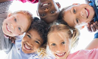 Closeup face of happy multiethnic children embracing each other and smiling at camera. Team of smiling kids embracing together i