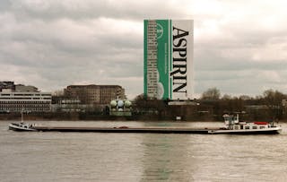 A vessel on the river Rhine floats past an administration building of the Bayer AG chemical company ..