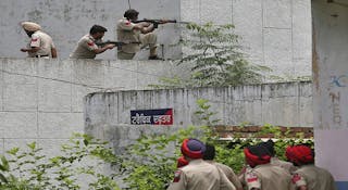 Indian policemen take their positions next to a police station during a gunfight at Dinanagar town