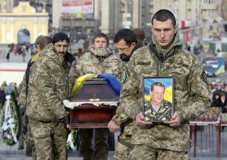 Ukrainian soldiers carry the coffin bearing the body a member of self-defence battalion "Aydar" during a funeral ceremony at Ind