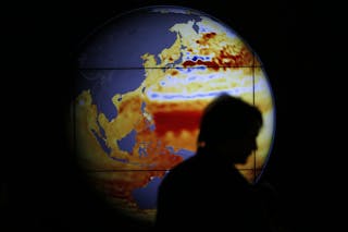 A woman walks past a map showing the elevation of the sea in the last 22 years during the World Climate Change Conference 2015 a