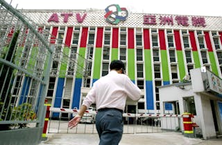 MAN WALKS PAST ASIA TELEVISION BUILDING IN HONG KONG.