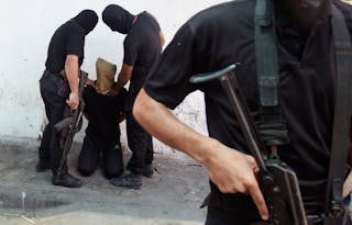 Hamas militants grab a Palestinian suspected of collaborating with Israel in Gaza City