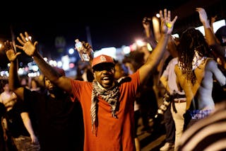 Demonstrators raise their arms as they protest against the shooting of Michael Brown in Ferguson, Missouri