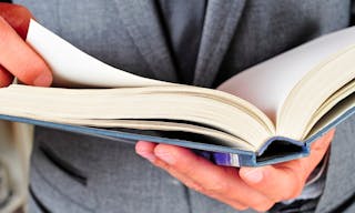 a man wearing a suit reading a book