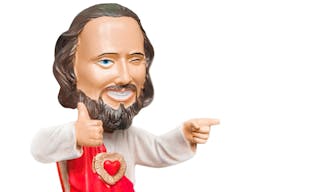 Statuette of a smiling Jesus showing a gesture of the thumbs up. Isolated on white