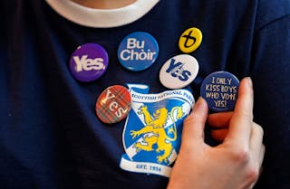 A party supporter displays some of her badges at the Scottish Nationalist Party annual party conference in Perth