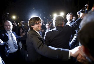 New Catalan President Carles Puigdemont salutes supporters next to outgoing Catalan President Artur Mas after the investiture se