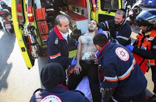 Israeli medics wheel a wounded man to an ambulance at the scene of a stabbing attack in Tel Aviv