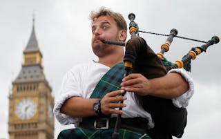 Bagpiper and busker David Whitney of Aberdeen, Scotland, plays the bagpipes near Big Ben and the Houses of Parliament in central