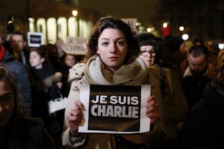 Woman holds a placard during a vigil to pay tribute to the victims of a shooting by gunmen at the offices of weekly satirical ma