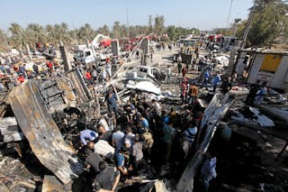 Residents gather at the site of a bomb attack at a checkpoint in the city of Hilla