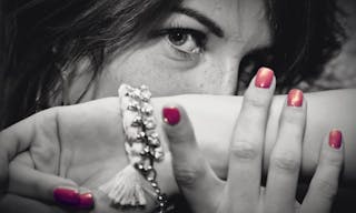 Beautiful young woman portrait with jewellery, close up, eyes focus. Fashion, beauty. Black and white with red nails