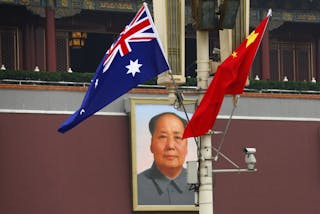 The Australian national flag flies next to the Chinese national flag in front of the giant portrait of former Chairman Mao Zedon