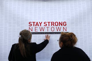 A woman touches a printout of messages from teenagers around the United States at a memorial for the victims of the Sandy Hook E