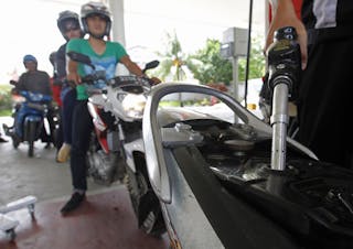 An employee of state-owned Pertamina refuels a motorcycle at its petrol station in Jakarta