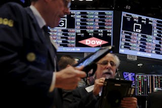 Traders work below a board displaying the Dow Chemical logo on the floor of the New York Stock Exchange shortly after the openin