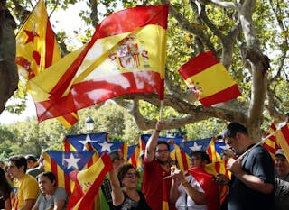 Catalonian separatist supporters and Spanish unionist supporters wave flags in front of Catalonia's Parliament before the approv