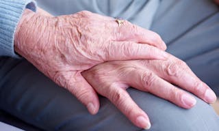 hand of an elderly woman holding the hand of an elderly man.