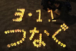 People arrange electric candles to form a message during a candle light demonstration to pay tribute to the victims of the March