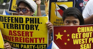 Protesters display placards as they march to the Chinese consulate office in Makati