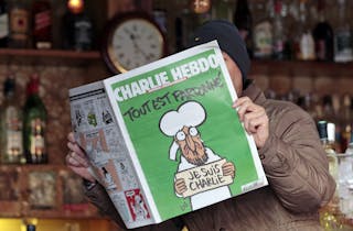 A man poses with the new issue of French satirical weekly Charlie Hebdo at a cafe in Nice