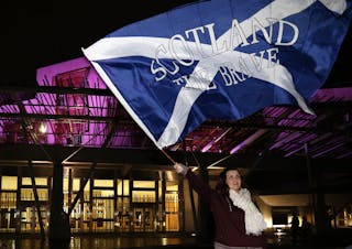 A supporter from the "Yes" Campaign waves a Scottish Saltire flag outside the Scottish Parliament in Edinburgh, Scotland