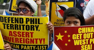 Protesters display placards as they march to the Chinese consulate office in Makati