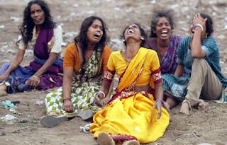 Women mourn the death of victims killed when a tsunami hit on Sunday during their burial in ...