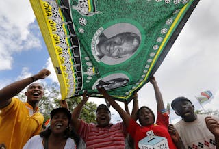 Mourners wave a flag bearing images of former South African President Nelson Mandela before a funeral procession through the cen