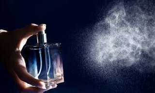 Woman spraying perfume on dark background, closeup - 圖片