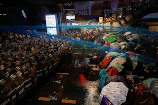 警方在噴灑的水柱中混有催淚劑，民眾用雨傘阻擋