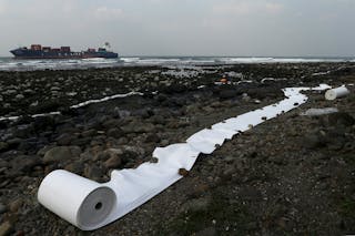 Oil-absorbing materials are seen laid out along a rocky beach after an oil leaked from a cargo ship owned by TS Lines Co, off th